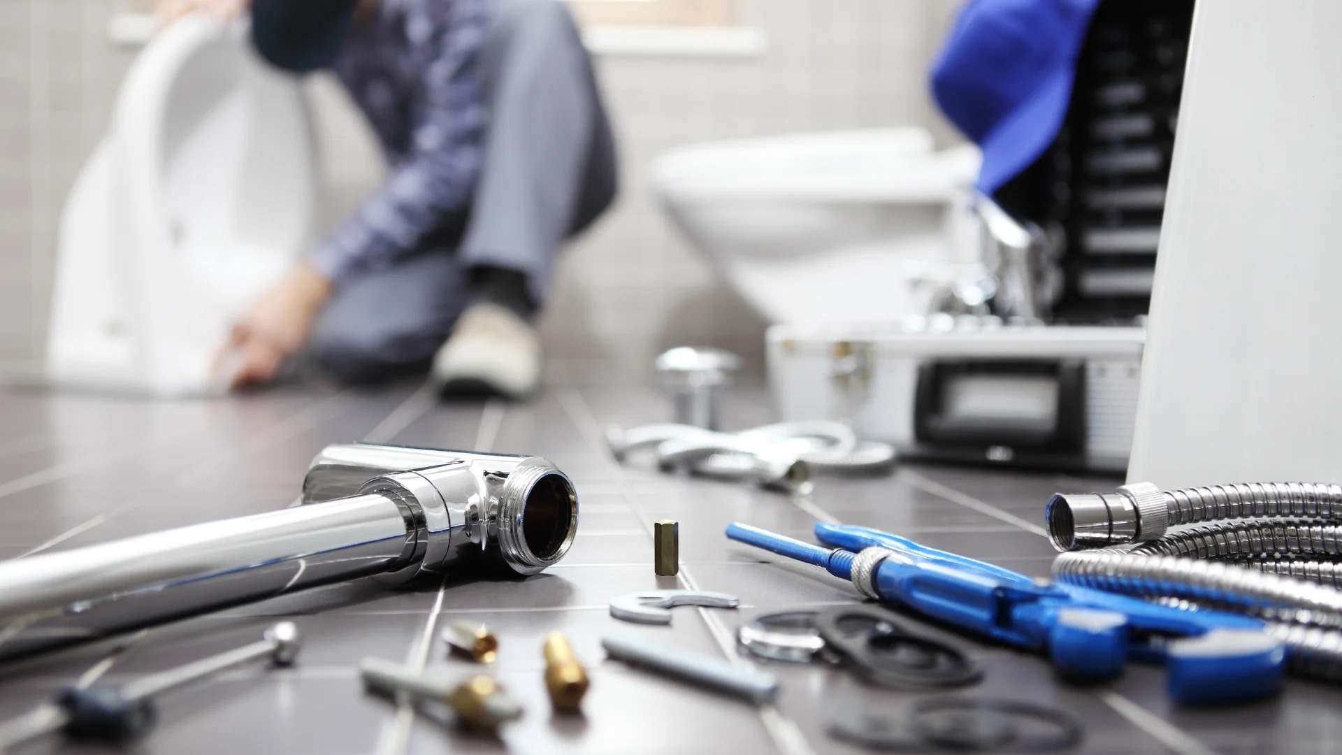 Reparaciones de fontanería en Sevilla: fontanero ajustando sanitario con herramientas en el suelo